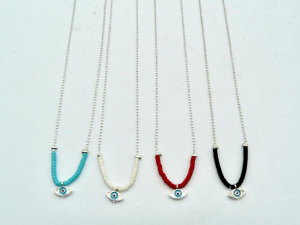 Four Silver-Plated Brass Thin Chain Necklaces With Lobster Clasp Adjustable Closure and Different Bead Colors: One With Black Beads, Another With White Beads, a Third With Turquoise Beads, and the Last One With Red Beads. The Central Piece of Each Necklace is an Eye of Horus Charm and is Encased in a Layer of Silver Plated Brass